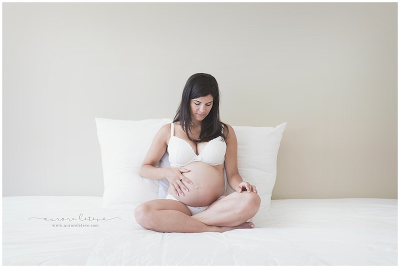 Photo d'une femme enceinte en lingerie avec une main sur son ventre par photographe grossesse à Lyon